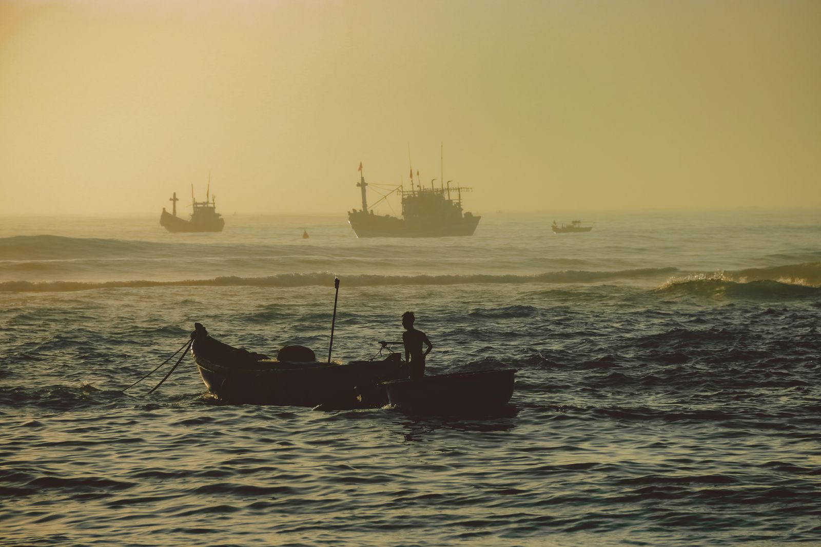 Barcos de pesca silhuetados ao nascer do sol no mar calmo