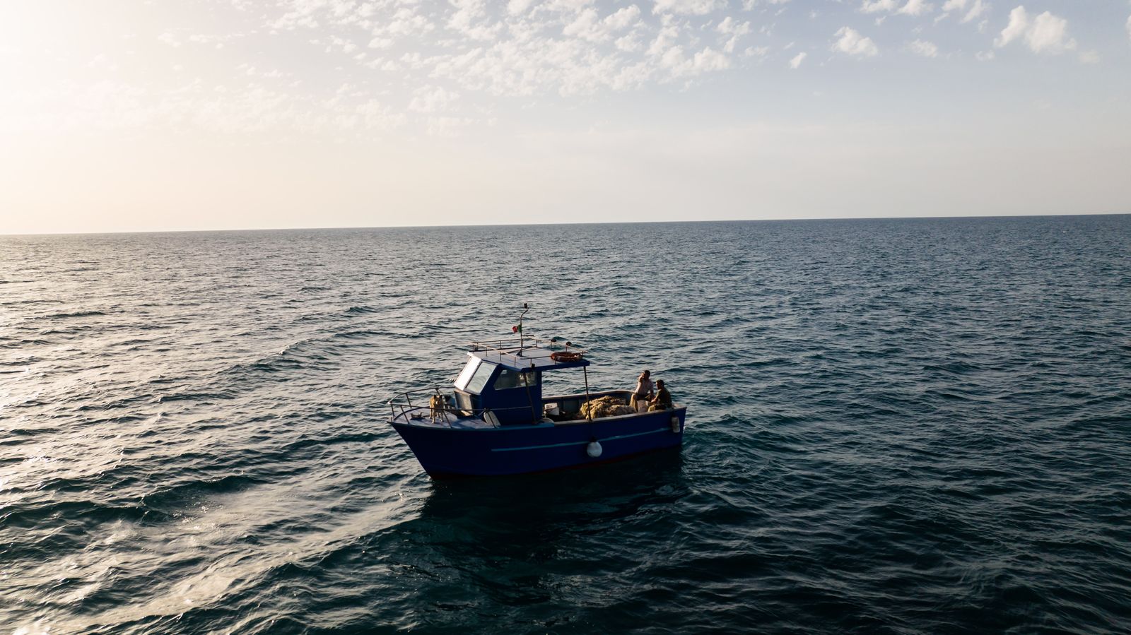 Barco de pesca solitário num oceano calmo sob céu sereno