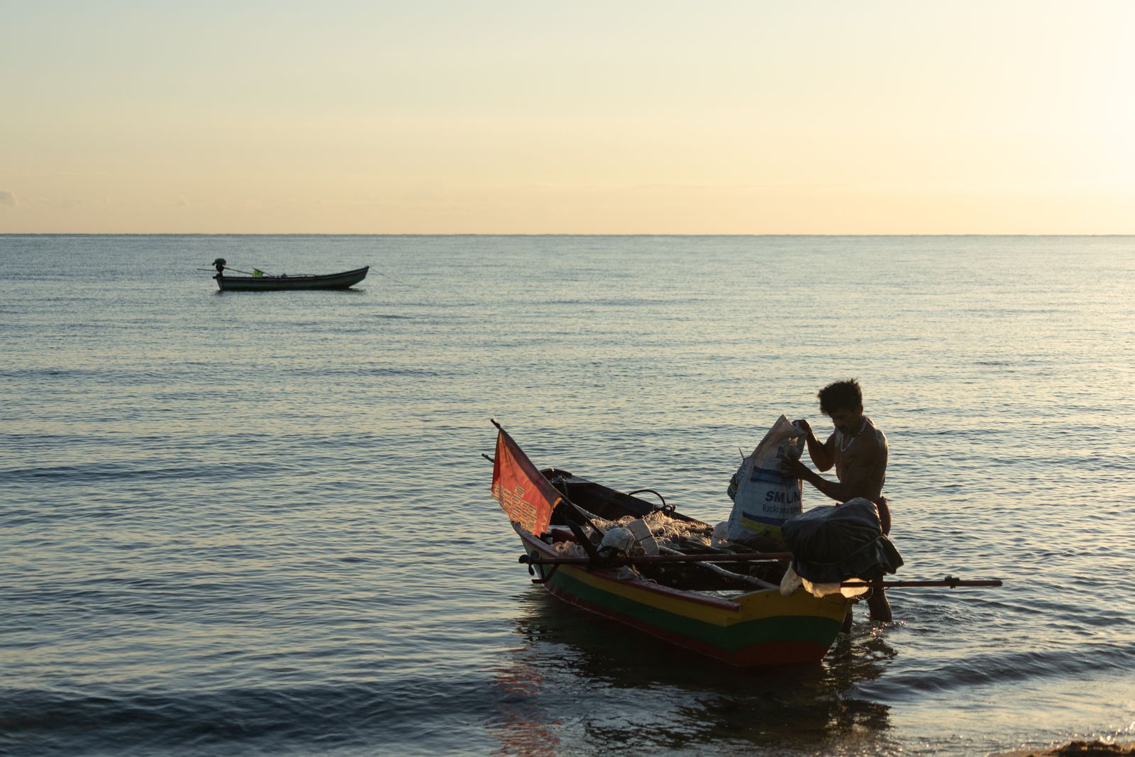 Pescador solitário a preparar o barco ao nascer do sol