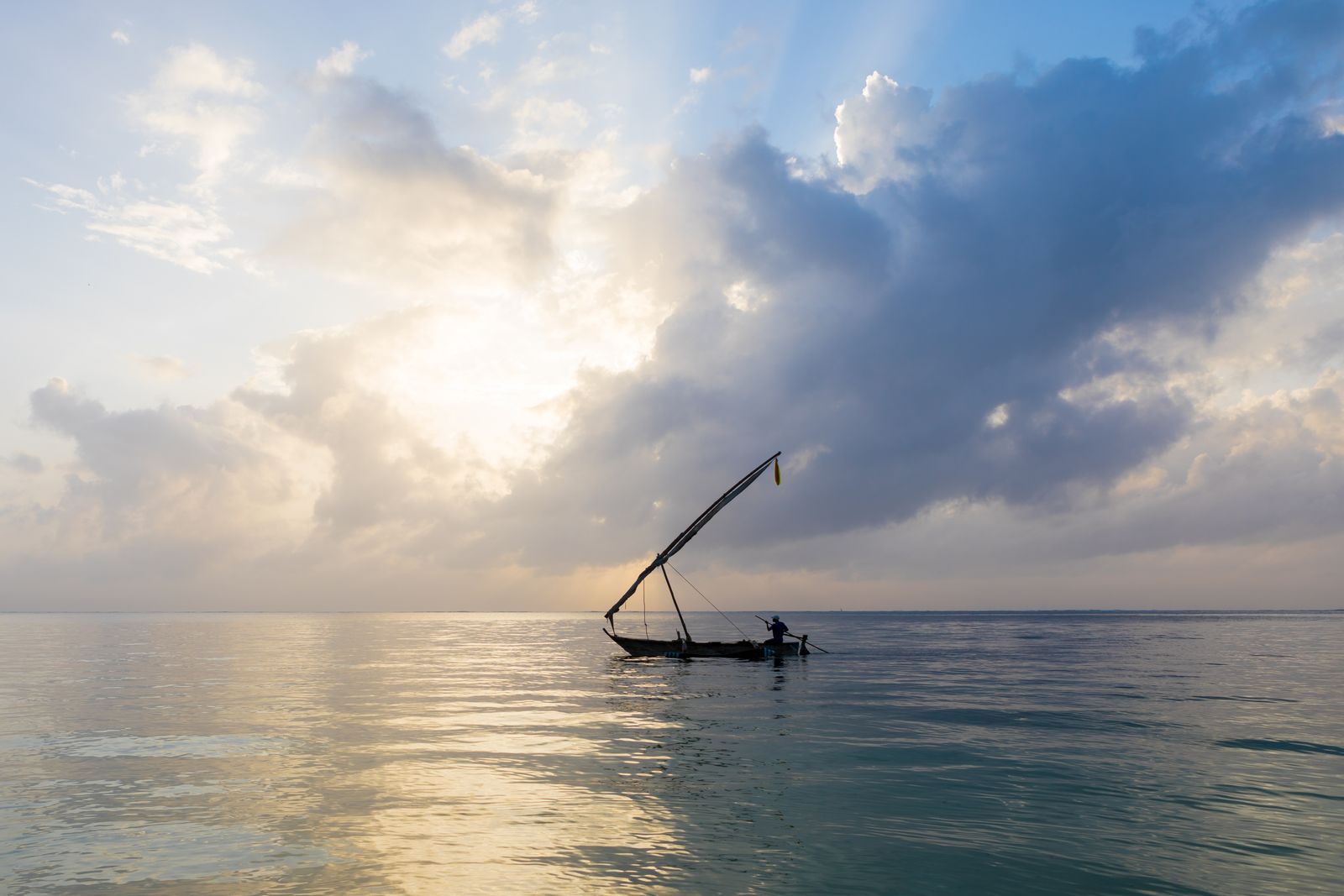 Pescador num dhow tradicional ao nascer do sol em Mombasa